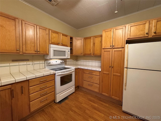 kitchen with white appliances, ornamental molding, tile countertops, and light hardwood / wood-style floors