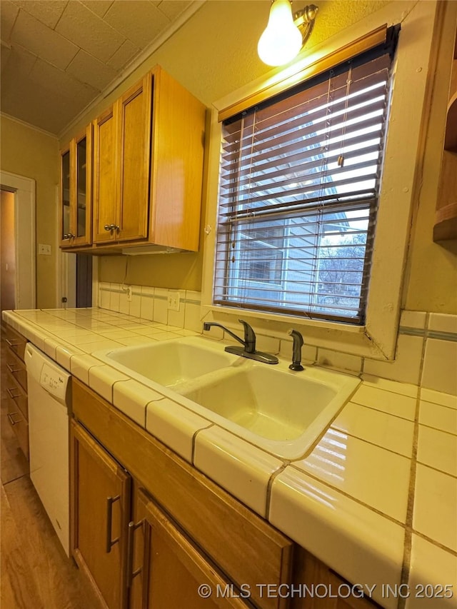 kitchen featuring sink, crown molding, tile counters, and dishwasher