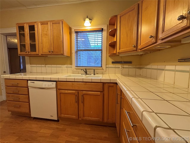 kitchen with sink, tile counters, white dishwasher, and light hardwood / wood-style floors