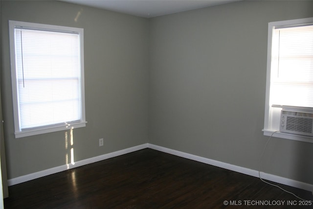 spare room featuring a healthy amount of sunlight, dark wood-type flooring, and cooling unit