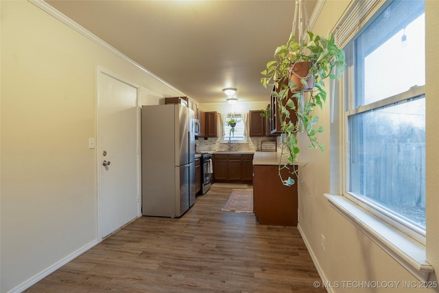 kitchen featuring sink, crown molding, appliances with stainless steel finishes, dark hardwood / wood-style flooring, and decorative backsplash