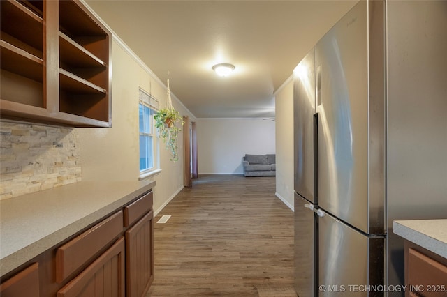 hallway with light hardwood / wood-style flooring and ornamental molding