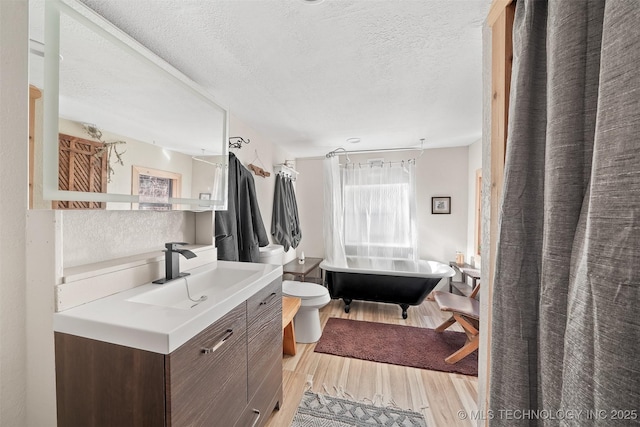 full bathroom with vanity, wood-type flooring, a textured ceiling, toilet, and shower / bath combo with shower curtain