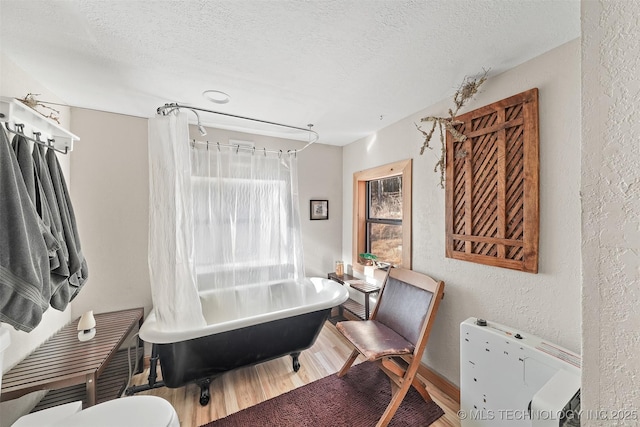 bathroom with toilet, separate shower and tub, hardwood / wood-style floors, and a textured ceiling