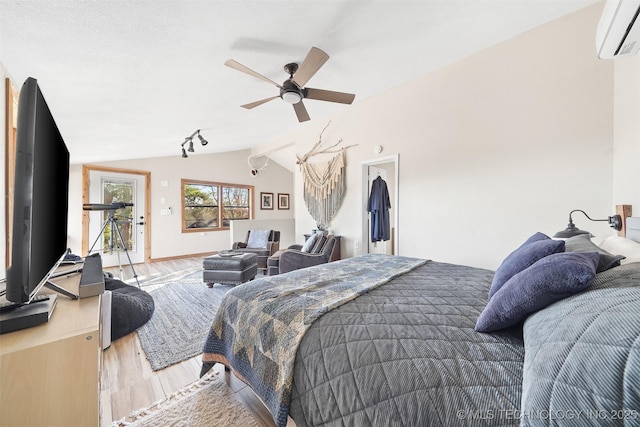 bedroom with lofted ceiling, a wall mounted AC, access to outside, hardwood / wood-style flooring, and ceiling fan