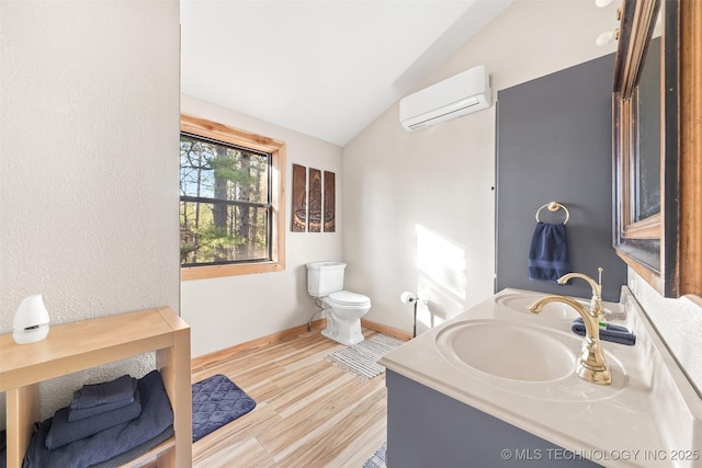 bathroom featuring wood-type flooring, lofted ceiling, vanity, toilet, and a wall unit AC