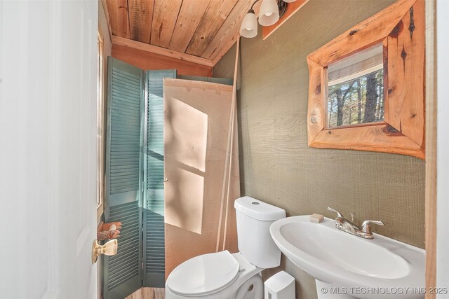 bathroom with wood ceiling, toilet, and sink