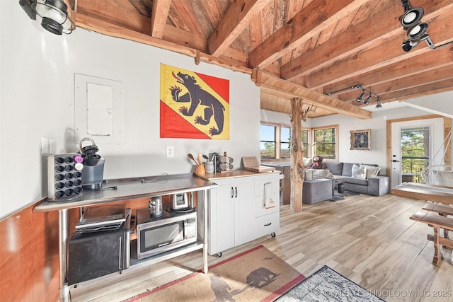 kitchen with white cabinetry, light wood-type flooring, beam ceiling, and stainless steel counters