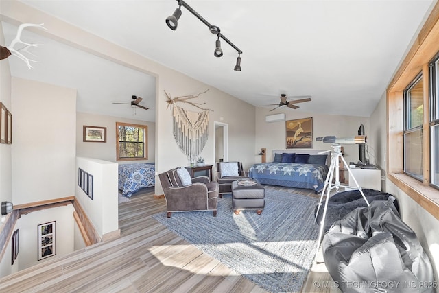 bedroom with vaulted ceiling, light hardwood / wood-style flooring, an AC wall unit, track lighting, and ceiling fan