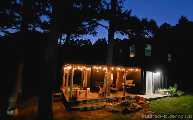 back house at night featuring a patio