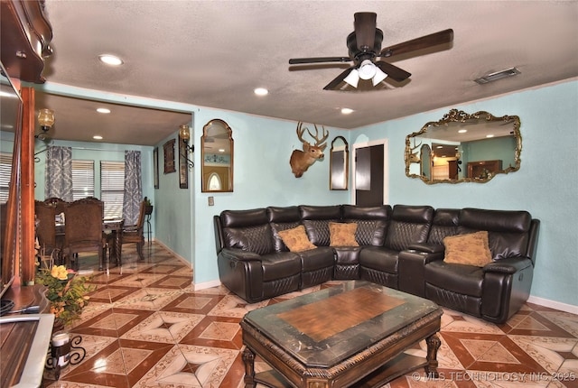 living room featuring ceiling fan and a textured ceiling