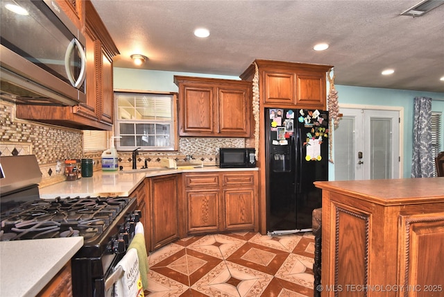 kitchen featuring sink, tasteful backsplash, black appliances, a textured ceiling, and french doors