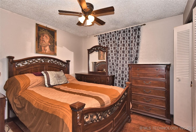 bedroom featuring dark hardwood / wood-style flooring, ceiling fan, and a textured ceiling