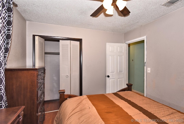 bedroom featuring ceiling fan, dark wood-type flooring, a closet, and a textured ceiling