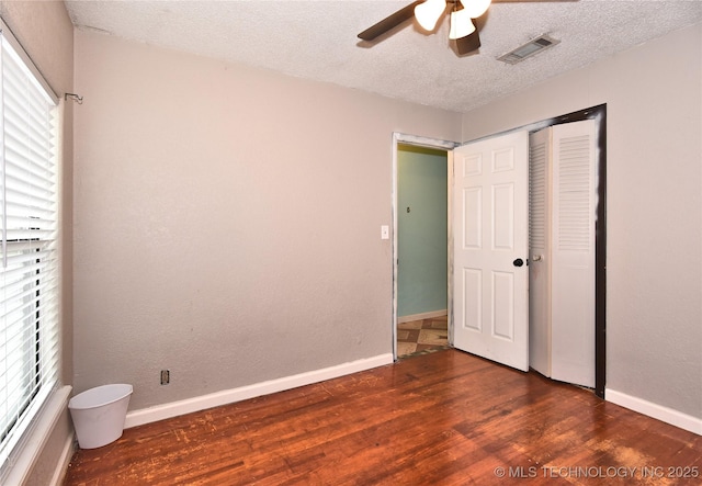 unfurnished bedroom with ceiling fan, a closet, dark hardwood / wood-style flooring, and a textured ceiling