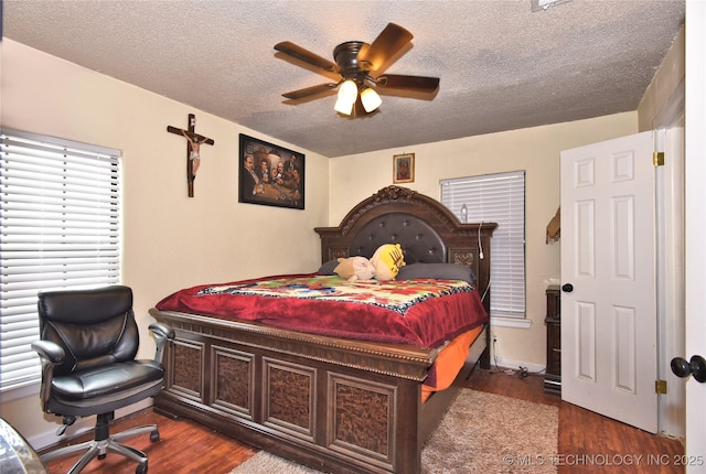 bedroom with dark wood-type flooring, ceiling fan, and a textured ceiling