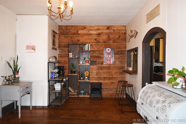 dining area featuring dark hardwood / wood-style floors, wooden walls, and a chandelier