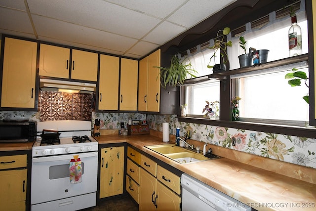 kitchen featuring dishwashing machine, sink, a paneled ceiling, white gas range, and decorative backsplash