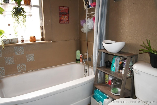 bathroom featuring toilet and a washtub