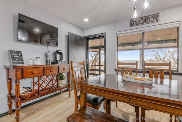 dining area with a textured ceiling and light wood-type flooring