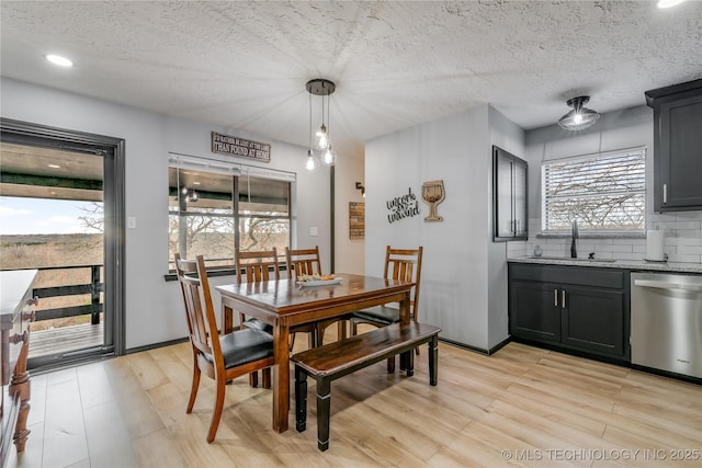 dining space with light hardwood / wood-style floors, sink, and a textured ceiling