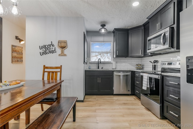 kitchen featuring stainless steel appliances, tasteful backsplash, light stone countertops, and sink