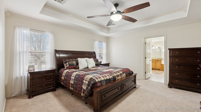 carpeted bedroom featuring ornamental molding, connected bathroom, and a raised ceiling