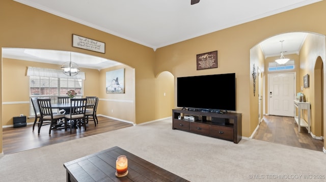 living room featuring crown molding, carpet floors, and an inviting chandelier