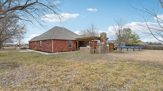 back of property featuring a yard and a pergola