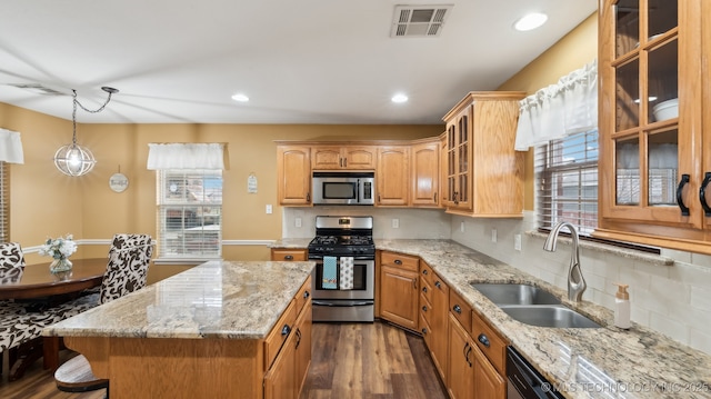 kitchen featuring a kitchen island, appliances with stainless steel finishes, pendant lighting, sink, and light stone countertops