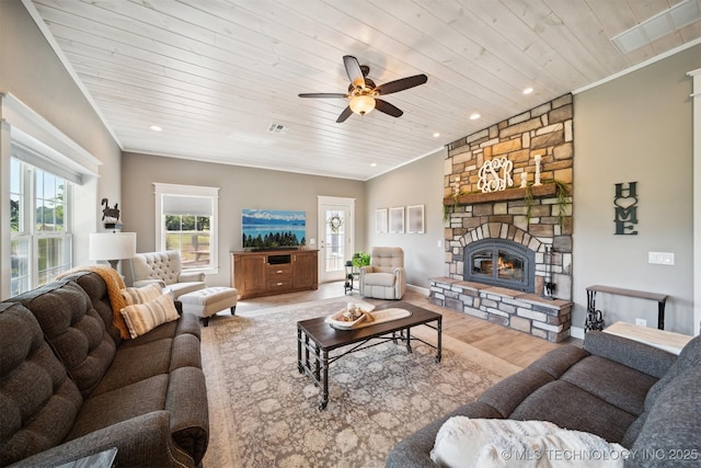 living room featuring ornamental molding, a stone fireplace, wood-type flooring, and wood ceiling