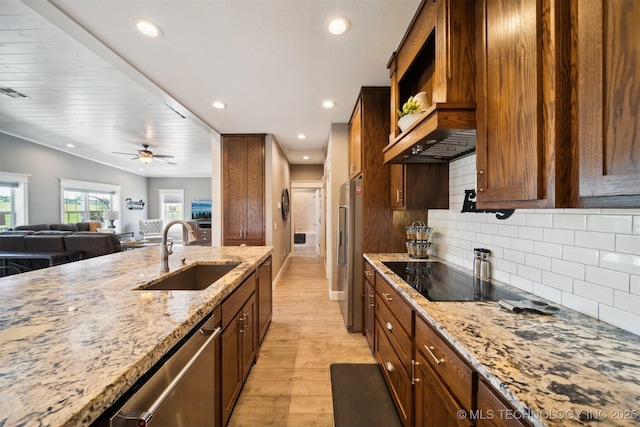 kitchen featuring sink, tasteful backsplash, stainless steel appliances, light stone countertops, and light hardwood / wood-style floors