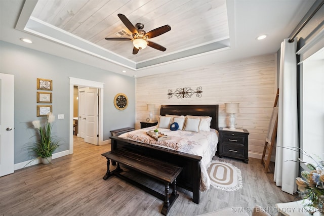 bedroom featuring wood walls, a tray ceiling, light hardwood / wood-style flooring, and wooden ceiling