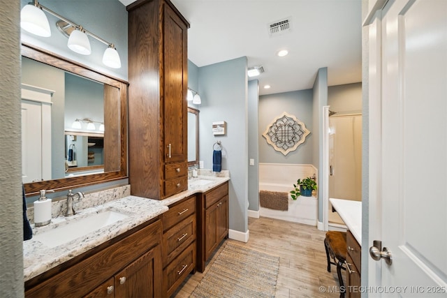 bathroom with vanity, wood-type flooring, and plus walk in shower