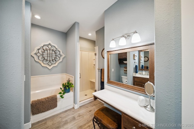 bathroom featuring hardwood / wood-style flooring, vanity, and shower with separate bathtub