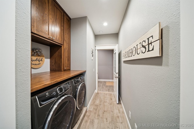 laundry area featuring independent washer and dryer, light hardwood / wood-style floors, and cabinets