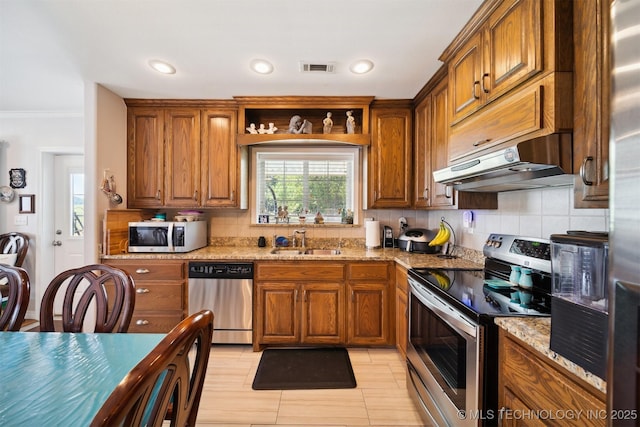 kitchen with stainless steel appliances, light stone countertops, sink, and decorative backsplash