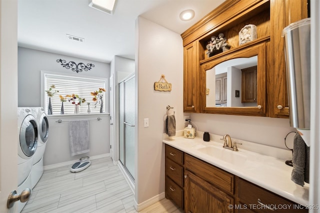 bathroom featuring vanity, a shower with shower door, and washing machine and clothes dryer