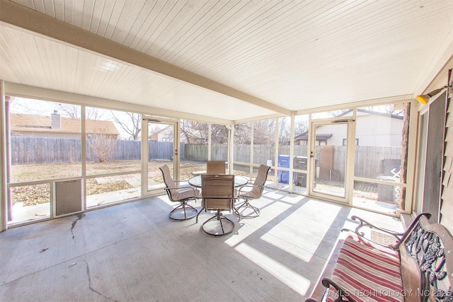 unfurnished sunroom featuring beamed ceiling