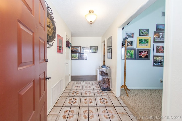 hallway with light tile patterned floors and a textured ceiling