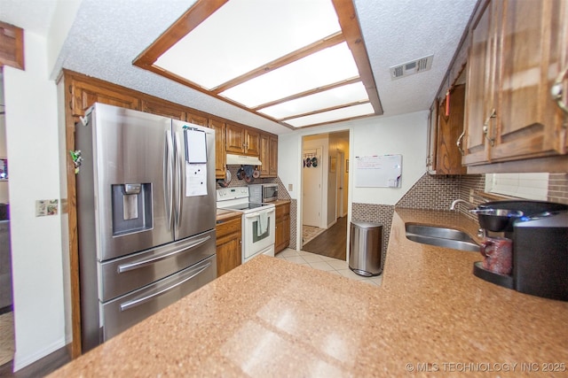 kitchen with appliances with stainless steel finishes, sink, a textured ceiling, and decorative backsplash