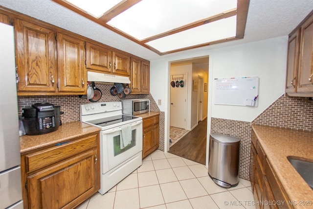 kitchen with tasteful backsplash, stainless steel appliances, a textured ceiling, and light tile patterned floors