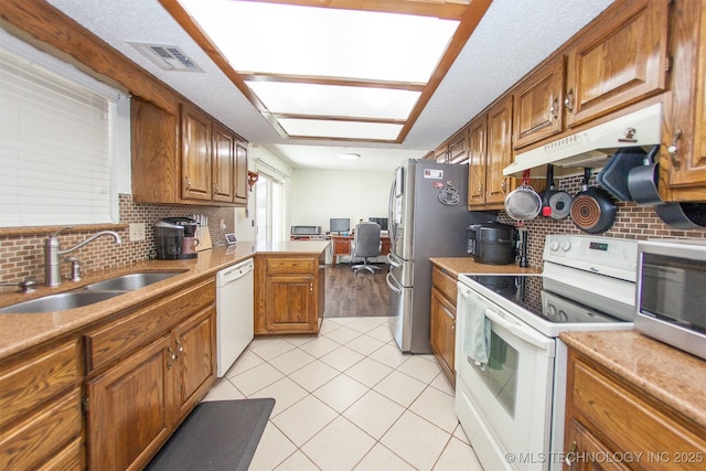 kitchen with sink, stainless steel appliances, a textured ceiling, light tile patterned flooring, and decorative backsplash