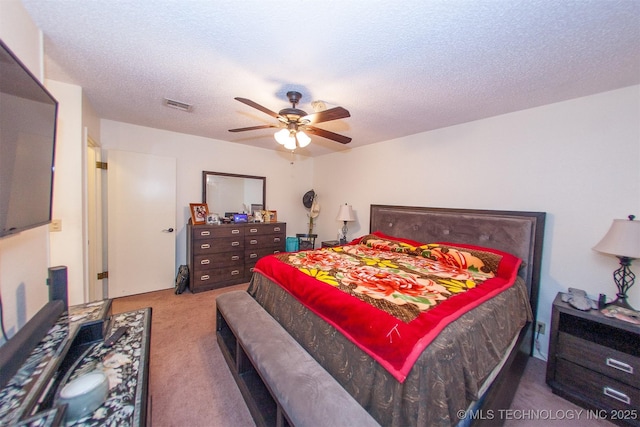 bedroom with ceiling fan, carpet, and a textured ceiling