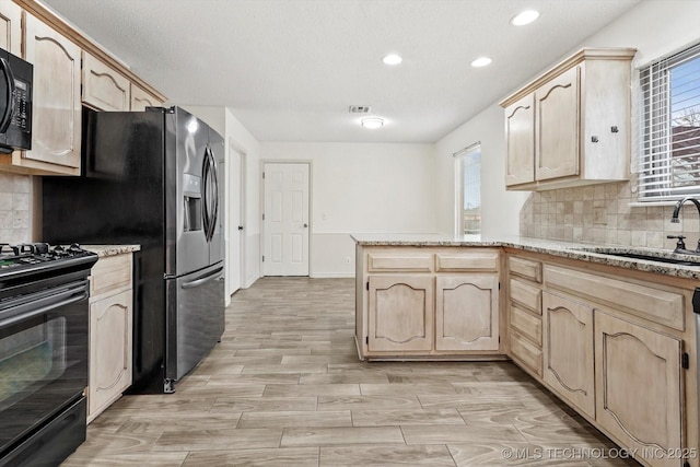 kitchen featuring light brown cabinetry, sink, black appliances, and kitchen peninsula