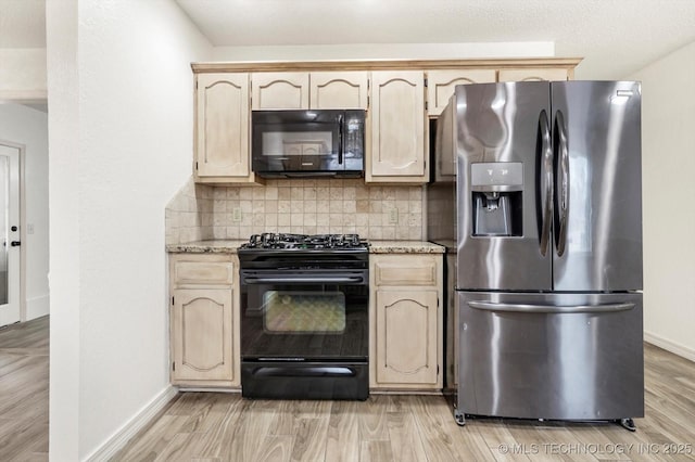 kitchen with light stone countertops, backsplash, light wood-type flooring, and black appliances