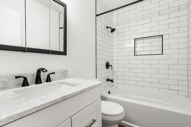 full bathroom featuring tiled shower / bath, vanity, and toilet