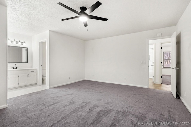 unfurnished bedroom featuring ceiling fan, ensuite bath, light carpet, and a textured ceiling