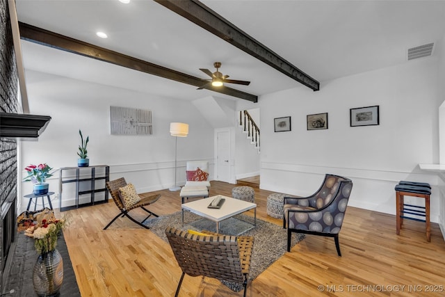 living room with beamed ceiling, ceiling fan, and light wood-type flooring