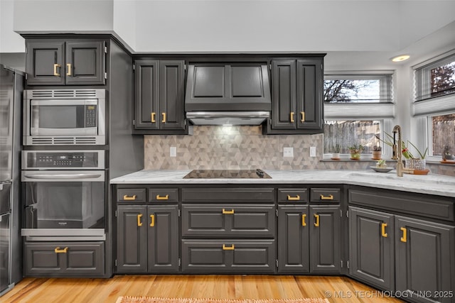 kitchen with sink, stainless steel appliances, tasteful backsplash, light hardwood / wood-style floors, and light stone countertops